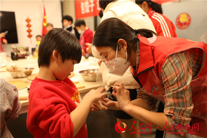 圖為容西片區(qū)飛泉社區(qū)組織回遷居民包餃子。人民網 楊華龍攝